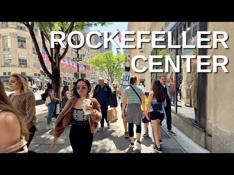 Videothumbnail met de tekst Rockefeller Center en voorbijgangers op straat langs winkels bij het Rockefeller Center op een zonnige dag