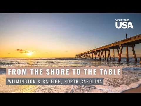 Een houten pier steekt ver de zee in terwijl de zon ondergaat bij Wilmington, North Carolina