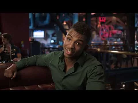 Een man in groen overhemd leunt glimlachend op een bank in een sfeervol verlicht restaurant in Orlando