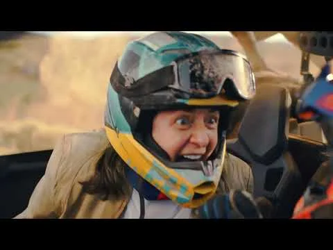 Videominiatuur met een persoon met helm en stofbril die opgewonden kijkt tijdens een offroad rit in een buggy door de woestijn
