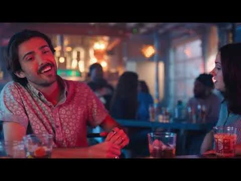 Een groep vrienden lacht en drinkt cocktails aan een tafel in een sfeervolle bar in Texas
