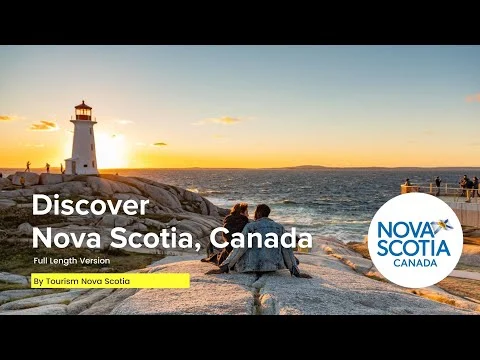 Videominiatuur met de tekst Discover Nova Scotia Canada en een stel dat op de rotsen bij de vuurtoren van Peggy's Cove naar de zonsondergang kijkt