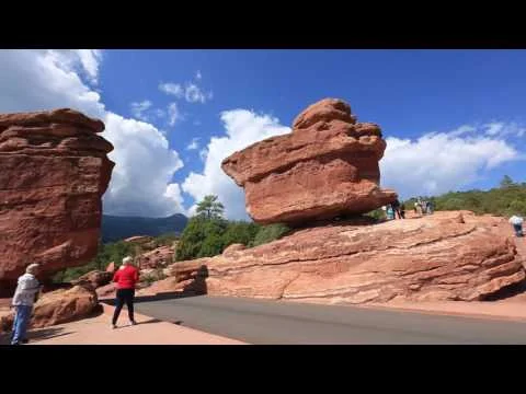 Videominiatuur met bezoekers bij de bekende balancerende rotsformatie van Garden of the Gods in Colorado Springs onder een blauwe lucht