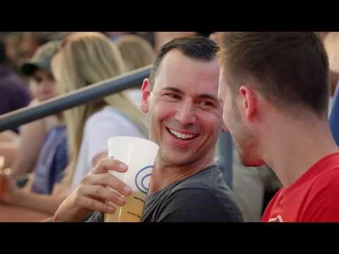 Videobeeld van twee lachende mannen met een drankje in de tribune tijdens een honkbalwedstrijd in Ohio