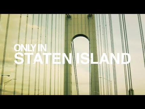 Videobeeld met de tekst Only in Staten Island over een close-up van de pijler van de Verrazzano Narrows Bridge