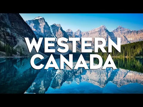 Een turquoise bergmeer in West-Canada weerspiegelt de omringende rotsachtige bergketen en dennenbossen onder een strakblauwe lucht
