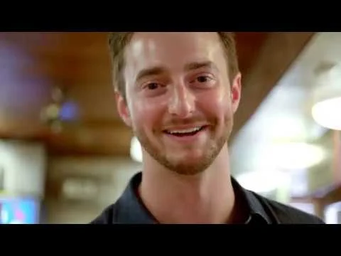 Een glimlachende jongeman met baard staat in een gezellig verlicht restaurant in West Virginia