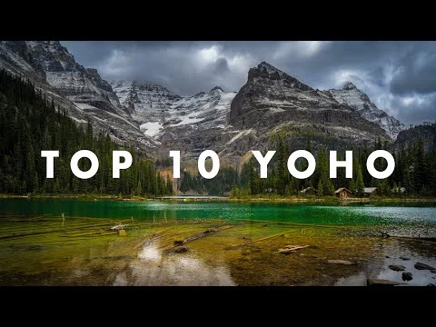 Uitzicht over een helder turquoise meer met houten hutjes aan de oever, omgeven door dennenbos en besneeuwde bergtoppen in Yoho National Park