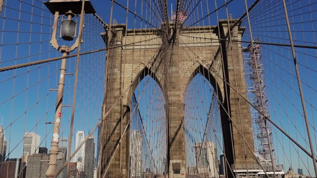 Close-up van de gotische stenen boogpijler van de Brooklyn Bridge met kabels en de skyline van Manhattan op de achtergrond