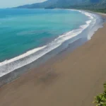 Luchtfoto van golven op een verlaten zandstrand met regenwoud en palmbomen aan de Pacifische kust van Costa Rica