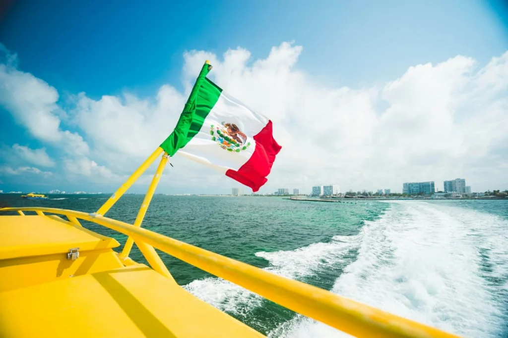 Een wapperende Mexicaanse vlag op het achterdek van de veerboot naar Cozumel, met Cancún op de achtergrond
