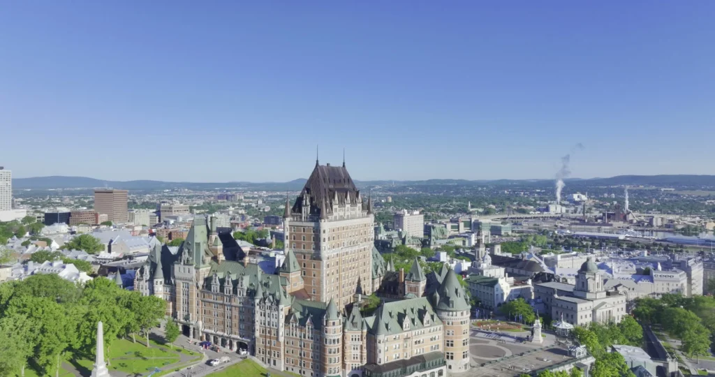 Luchtfoto van het kasteelhotel Chateau Frontenac met op de achtergrond de skyline van Quebec City onder een strakblauwe lucht