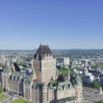 Luchtfoto van het kasteelhotel Chateau Frontenac met op de achtergrond de skyline van Quebec City onder een strakblauwe lucht