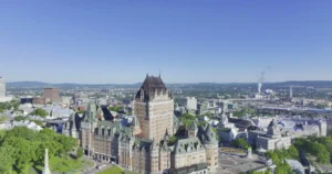 Luchtfoto van het kasteelhotel Chateau Frontenac met op de achtergrond de skyline van Quebec City onder een strakblauwe lucht