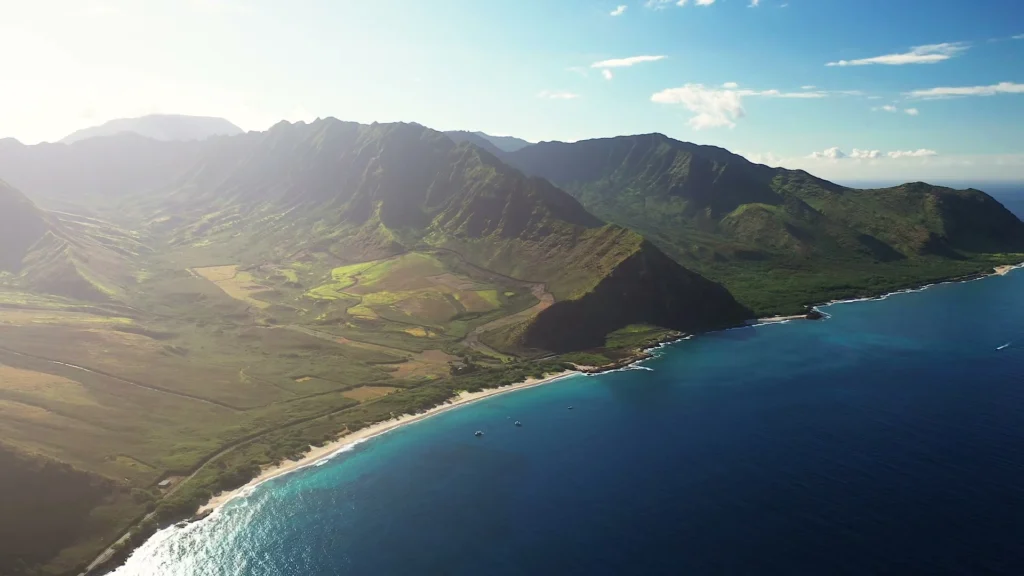 Luchtfoto van groene bergketens en een rustige baai aan de westkust van Oahu, Hawaii, bij zonsopgang