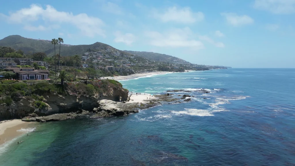 Luchtfoto van villa's op de kliffen boven een baai bij Laguna Beach in Zuid-Californie met zwemmers in het heldere water