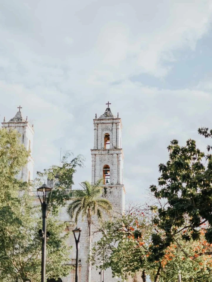 De witte torens van een koloniale kerk steken uit boven het groen van het centrum van Valladolid